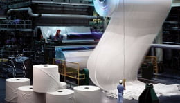 Industria vista desde el interior, con un rollo de celulosa envuelto alrededor de una máquina que ilustra el uso de lubricantes industriales Mobil
